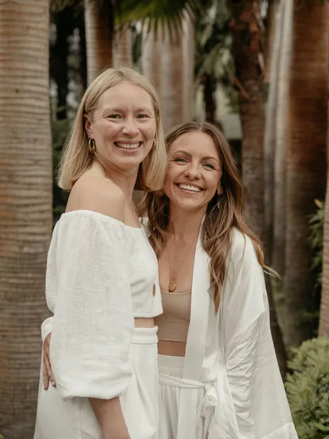 Yavi und Janina umarmen sich zwischen Palmen