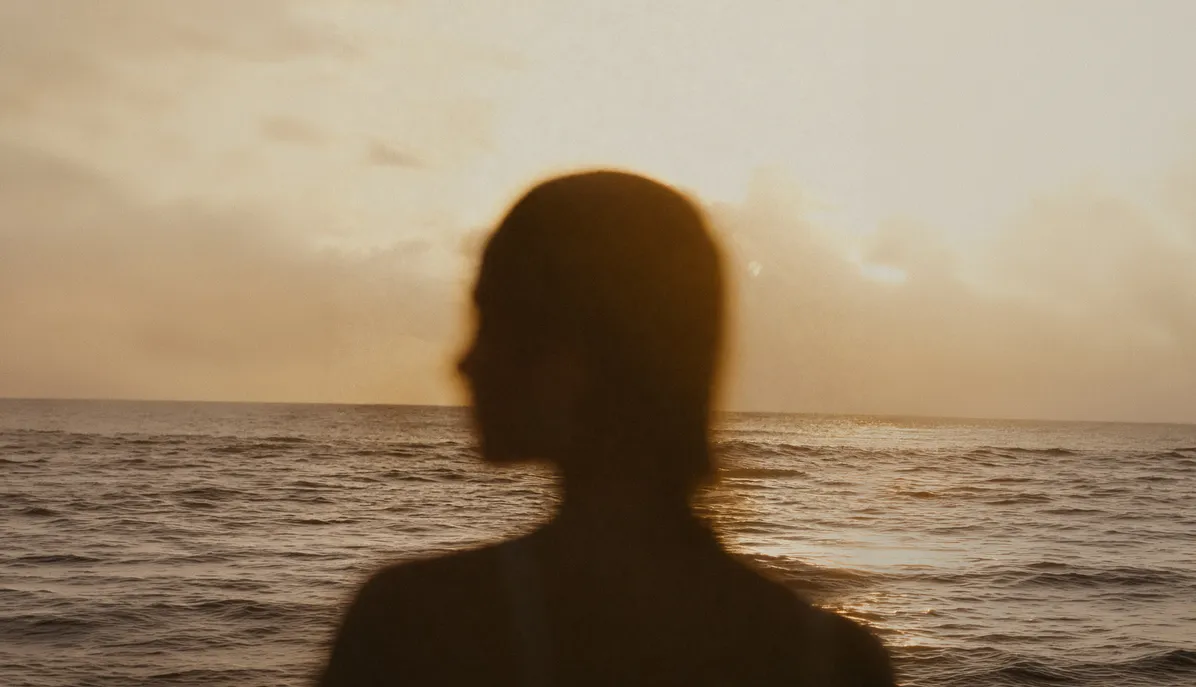 Silhouette einer Person vor dem Meer bei Sonnenuntergang